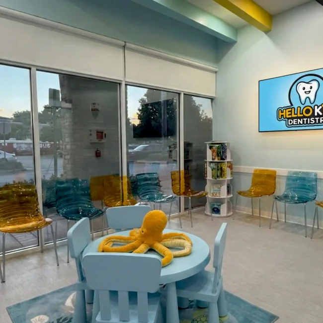 The modern and welcoming waiting room at Hello Kids Dentistry Pediatric Dentist in Pembroke Pines, FL, featuring a branded screen and a fun play area for kids dental care.